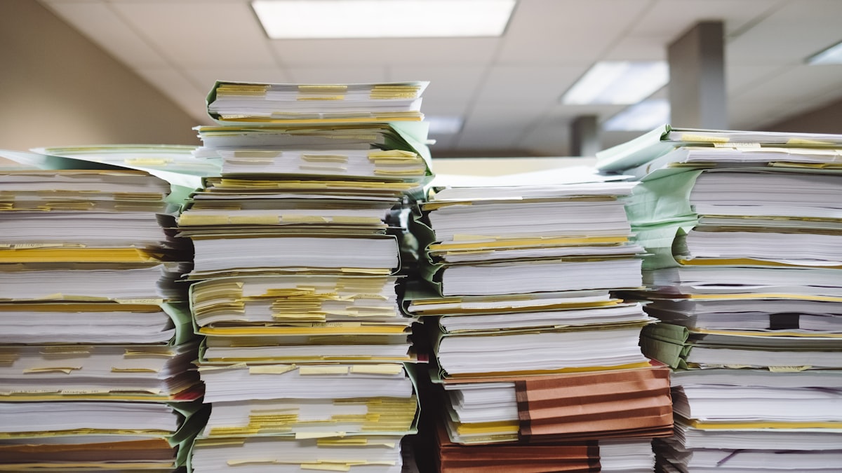 Pilhas de documentos em papel e pastas de arquivo, representando erros comuns ao orçar um sistema
