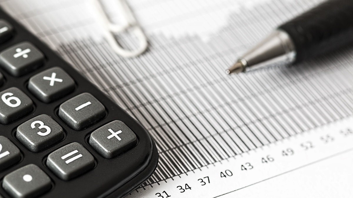 Calculadora, régua e caneta sobre planilha financeira, contexto de reforma tributária, IBS e CBS na gestão financeira da academia