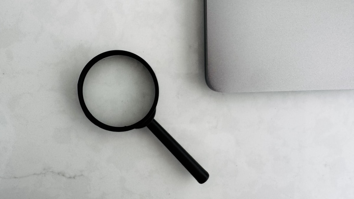 Lupa próxima a um laptop, simbolizando a análise detalhada do que um plano gratuito esconde